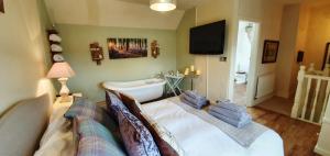 ein Wohnzimmer mit einer Badewanne, einem Bett und einem TV in der Unterkunft Hill End Cottages in Warslow