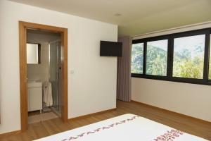 Schlafzimmer mit einem großen Fenster und einem Badezimmer in der Unterkunft Casa Encosta do Rio-ferias no Gerês in Vieira do Minho