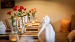 a table with red flowers in a vase on it at Bollenhuthotel Kirnbacher Hof in Wolfach