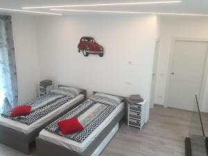 two beds in a room with a red car on the wall at Appartamento Oleandro in Arco