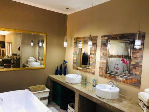 a bathroom with two sinks and two mirrors at Rooibos Retreat in Richards Bay