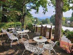 a deck with tables and chairs and a tree at McKinley Edwards Inn in Bryson City