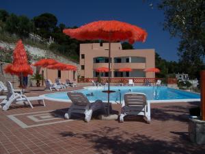 a swimming pool with chairs and umbrellas and a pool at Villa dei pini in Vieste