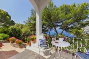 un patio con mesa, sillas y flores en Amore Rentals - Villa Polifemo en Capri
