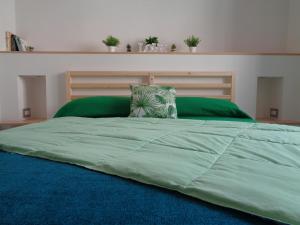 a large bed with a green comforter and a pillow at Affittacamere Badia in Foligno