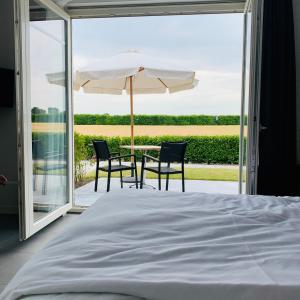 een slaapkamer met een tafel en stoelen en een parasol bij Groede B&B in Groede