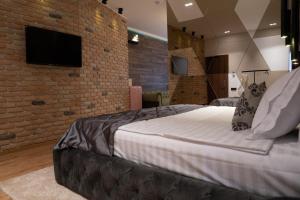 1 dormitorio con 1 cama grande y pared de ladrillo en The Residence Central Jacuzzi Boutique (Adult Only) en Cluj-Napoca
