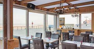 a restaurant with tables and chairs and a view of the beach at Hotel De Zeebries in Middelkerke