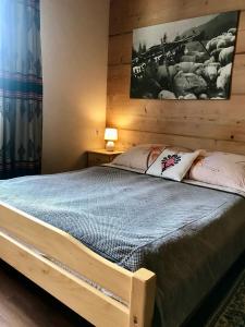 sypialnia z drewnianym łóżkiem z obrazem na ścianie w obiekcie Pokoje Gościnne U Jaśka w Zębie