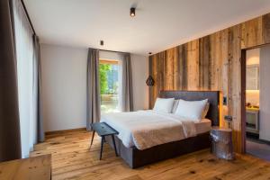 a bedroom with a bed with a wooden wall at Alpotel Dolomiten in Molveno