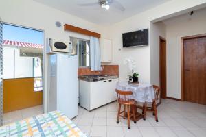 małą kuchnię ze stołem i lodówką w obiekcie Acapulco - Apartamentos em Bombinhas w mieście Bombinhas