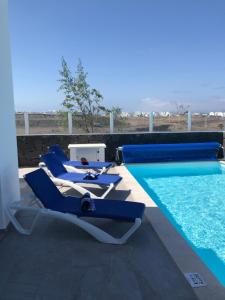 a pool with blue lounge chairs next to a swimming pool at Villa Blue Horizon in Playa Blanca