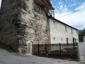 un edificio in pietra con una recinzione nera accanto di Guesthaus King Seti a Mestia