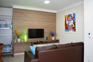 a living room with a couch and a flat screen tv at Sun Paradise - JTR in Maceió