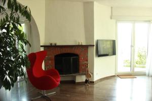 a red chair in a living room with a fireplace at Casa Creavita in Cademario