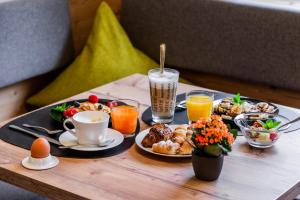 uma bandeja de alimentos e bebidas para o pequeno-almoço numa mesa em B&B Boutique Apartment Oberwiesen em Brunico