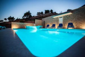 a swimming pool with three chairs and a house at Apartments Pušić in Omiš