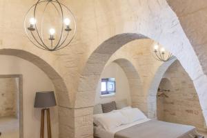洛科羅通的住宿－Trulli Nannì，一间卧室设有拱形天花板、一张床和两个吊灯。