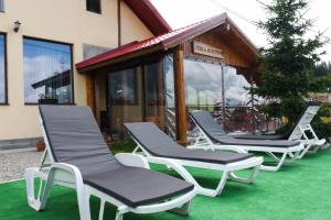 a group of lounge chairs sitting on a lawn at Perla Munților in Ranca