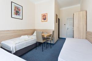 a hotel room with two beds and a table and chairs at Penzion Hotel Morrison in Pilsen