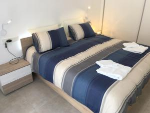 een groot bed met blauwe en witte lakens in een kamer bij Mini Villa "Las Palmeras" in Los Alcázares