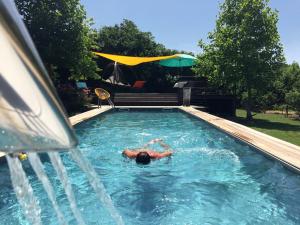 a man laying in a swimming pool next to a fountain at L'école des garçons in Maigné