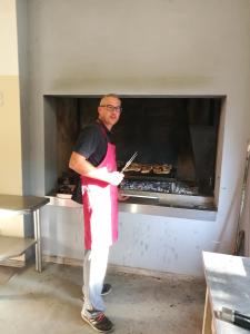 a man in an apron standing in front of an oven at Agriturismo Le Giarine in Fogliano Redipúglia