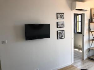 a flat screen tv on a white wall with framed pictures at Location corsica in Ajaccio