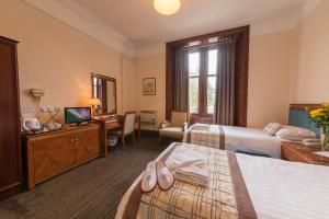 a hotel room with two beds and a desk at Muthu Royal Thurso Hotel in Thurso