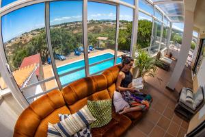 a woman sitting on a couch reading a book at Mayla Surf House in Aljezur