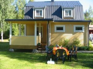 uma pequena casa amarela com uma mesa e cadeiras em Stuga på Brattmon em Sysslebäck