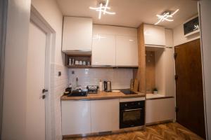 una cucina con mobili bianchi e un piano di lavoro di Royal Apartment a Bačka Palanka