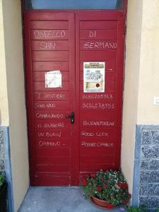 een rode deur met tekst aan de zijkant van een gebouw bij OSTELLO DI SAN GERMANO in Borgofranco dʼIvrea
