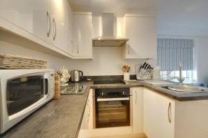 uma cozinha com armários brancos e um micro-ondas em Stunning apartment with 2 bedrooms, 2 en-suites, private parking em Bournemouth