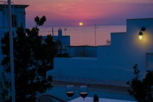 - un coucher de soleil sur l'océan avec 2 verres à vin dans l'établissement Pascaraymondo Suite Palace, à Gallipoli