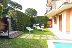 a yard with chairs and a hedge and a swimming pool at Etna Villa il Pino in Trecastagni