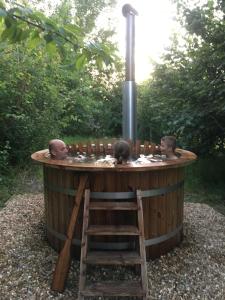 una vasca idromassaggio circolare in legno con tre uomini seduti dentro di Riverwood Farm Glamping Safari Tent a Talaton