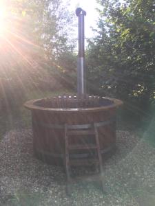 a wooden tub with a ladder in a garden at Riverwood Farm Glamping Safari Tent in Talaton