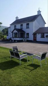 two chairs sitting in the grass in front of a building at Killoughagh House in Cushendall