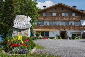 a sign in front of a house with flowers at Ferienpension Steiner in Weerberg