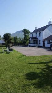 a white building with a parking lot next to a grass field at Killoughagh House in Cushendall