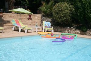 a swimming pool with several inflatables and two chairs at Mas des Petits Loups in Cabrières