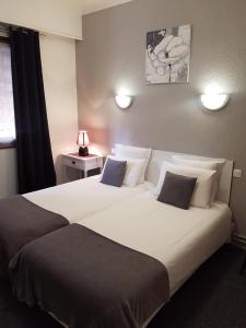 a hotel room with a large white bed with pillows at Hotel les Glycines in Prades