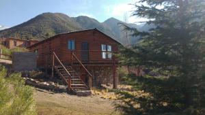 a wooden cabin with a staircase in front of a mountain at Balcones del Portezuelo in Potrerillos
