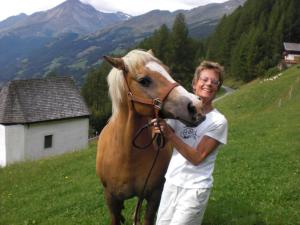 a man standing next to a brown horse in a field at Villa Talheim in Mallnitz