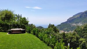a garden with a bench in the grass with mountains in the background at Chez Lia - Private garden and tub, sea view close to Villa Eva and Cimbrone, Ravello in Ravello
