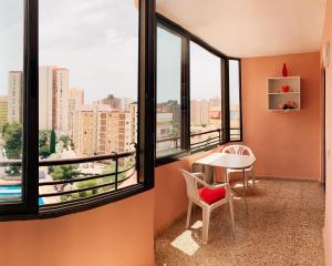 ベニドルムにあるEdificio Cadiz Benidormのテーブルと椅子、窓が備わる客室です。