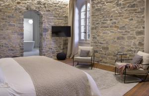 - une chambre avec un lit et un mur en pierre dans l'établissement Couvent de la Salette & Spa, à Millau