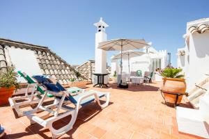 a patio with two chairs and an umbrella at Residencial Mares in Tavira