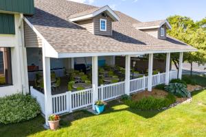 un porche cubierto con sillas y mesas en una casa en Tawas Bay Beach Resort & Conference Center, en East Tawas